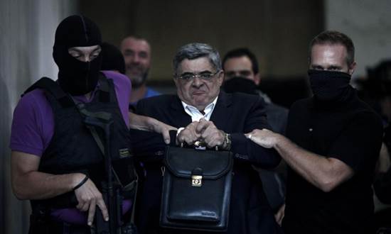Nikos Michaloliakos is escorted by masked police officers in Athens in September 2013.