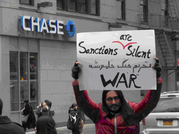 man holding Sactions Are Silent War sign in front of Chase
